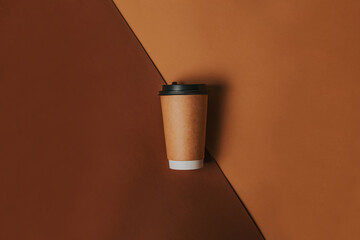 Brown paper coffee cup to go flat lay. A craft cup for hot drinks on a brown background with a place for text view from above. Stylish banner design for coffee and coffee shop
