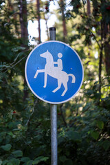 Ein Blau Weißes Schild mit einem Reitpferd markiert einen extra Reiterweg.