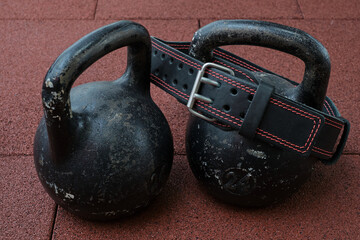 Fototapeta na wymiar kettlebells and Athletic belt on a floor. Bodybuilding equipment. Fitness or bodybuilding concept background. 