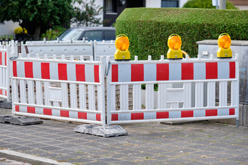 Street barriers with yellow warning lights standing in front of a construction site on the pavement...