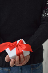 Moscow, Russia, January 2022, a man in a black sweater holds a gift with a red ribbon behind his back