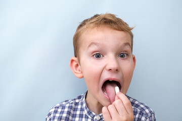 Cheerful boy drinks vitamins or medicines