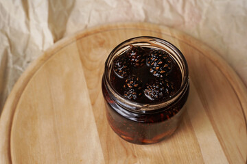 Eco friendly, healthy pine cone jam in a jar on a wooden board. Homemade jam