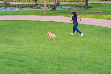 Young woman jogging with her golden puppy in the park