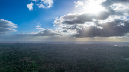 The winter sun breaking through the clouds, illuminates the trees and fields frozen in the cold with its dim light. High quality photo