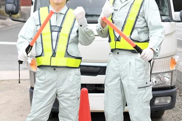 Fotobehang 誘導棒を持つ交通誘導をする作業服姿の男性達 © koumaru