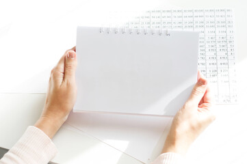 Obraz premium Hand holding notepad on white office desk table top view with copy space