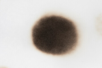 Paper burn black  stain isolated over the white background. Round paper burn mark close up