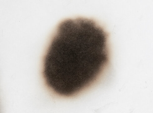 Paper burn black  stain isolated over the white background. Round paper burn mark close up