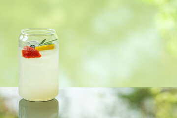 delicious juicy fresh lemon soda on glass table Blurred leaf reflection background