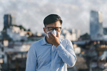 Asian man wearing the face mask to protect PM 2.5 dust and air pollution. problem dust smog in the...