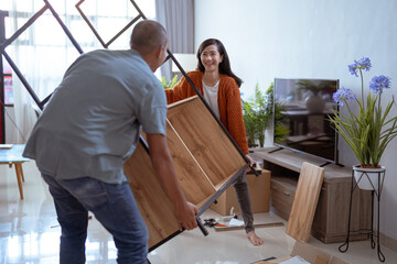 asian couple carry new furniture as they move