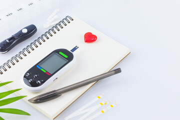 Diabetes control. Diabetic disease concept with Glucose meter, test strips for determining blood sugar levels, lancets and diary of control on a blue background with copy space. Selective focus