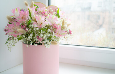 Delicate bouquet of pink lilies, white roses in a gift box on the window. Greeting card. Copy space