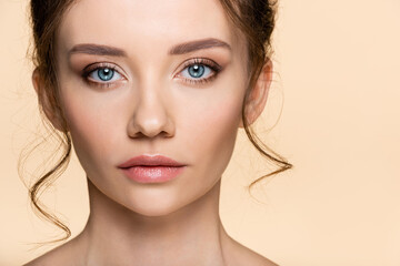 Fototapeta premium Young woman with visage looking at camera isolated on beige.
