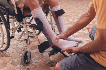 Obraz premium Parent helping wear protective equipment to prevent foot injuries to young man with a disability, Shoes to support foot deformities in people with disabilities and medical equipments concept.