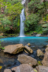 Catarata La Cangreja - Hidden waterfall surrounded by green trees, vegetation, rocks, leaves floating on green and clear water, Rincon de la Vieja National Park, Costa Rica Wilderness