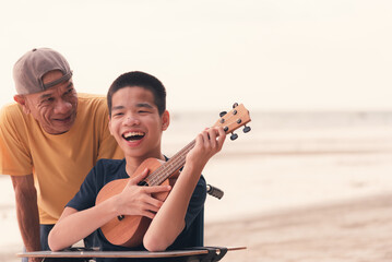 Young man with disability smiling happy face singing, playing music on the beach with parent on sea...