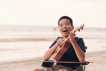 Young man with disability smiling with happy face singing, playing music on the beach, Beautiful sea background, Vacation on holiday with family activity and natural therapy and mental health concept.