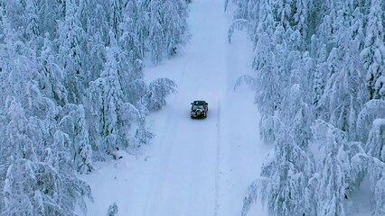 Aerial drone view following a SUV driving in arctic forest, cloudy, winter day in Lapland