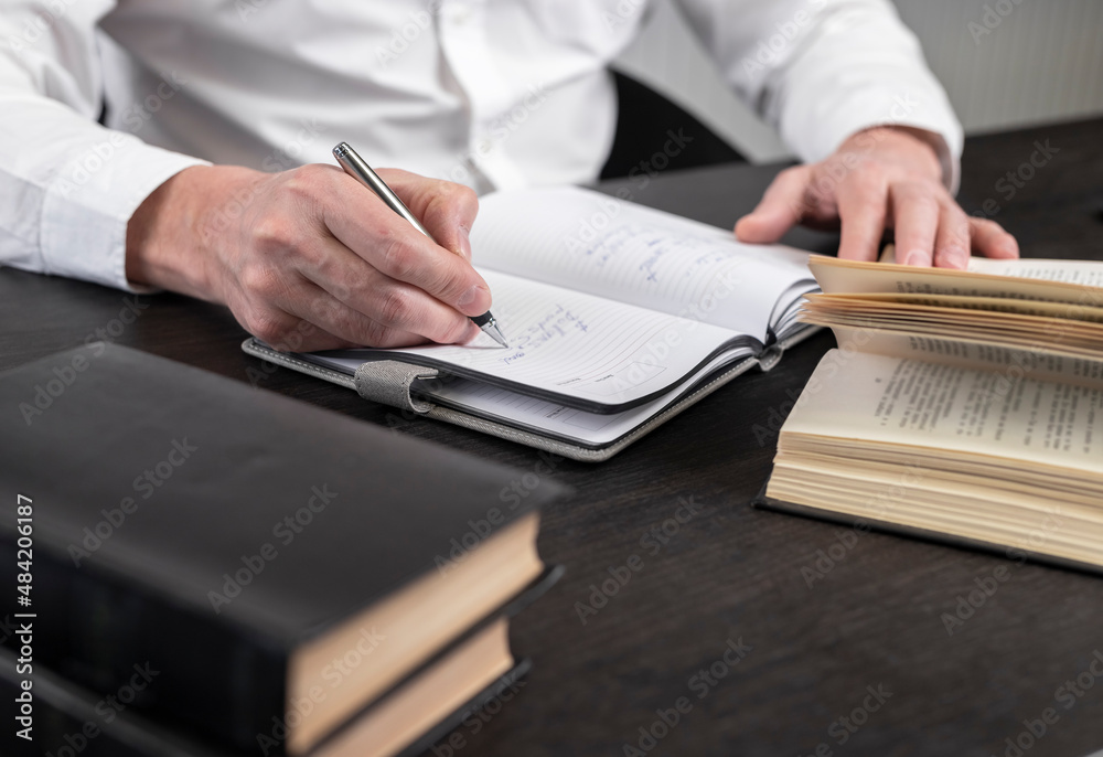 Poster man hands taking notes in planner. businessman sitting at table with books or codes at home or in of