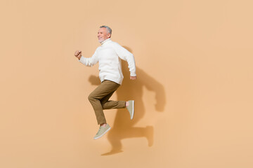 Full length body size view of attractive cheerful sportive man jumping running isolated on beige...