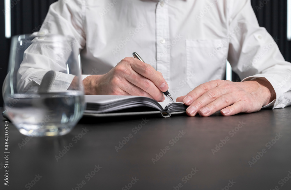 Poster Man hands taking notes in planner. Employee sitting at desk and writing plans. Business planning concept. . High quality photo