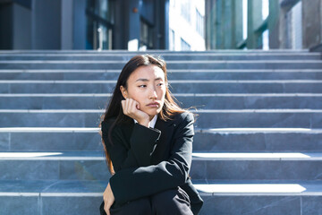 Fototapeta premium Asian woman with strong headdress sitting on stairs, sick and sad depressed businesswoman