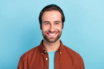 Portrait of young smiling positive guy in brown shirt laughing with perfect white veneer teeth isolated on blue color background
