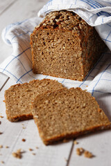 Sliced box bread from whole spelt flour, on a wooden table, with kitchen towel. Close-up with selective focus.