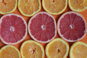Citrus fruits cut into slices on an orange surface.	