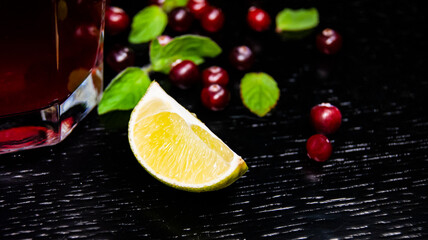 Glass with juice, lime wedge, mint and cranberries