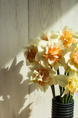 Bouquet of daffodils. Flowers on the background of a light wooden wall. Spring bouquet. Vertical. copy space. - 484211513