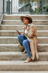 Woman taking notes and writing ideas in a notepad while sitting on the stairs in the street.