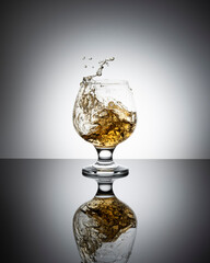 Splash of cognac in glass isolated on a light background