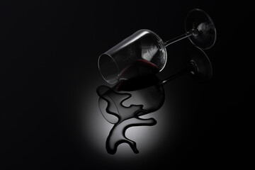 Spilled wine glass on a black background with reflection.