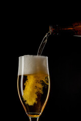 a beer pouring in a glass on a black background