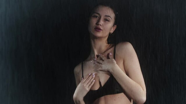 Attractive young woman with hot slim body walks towards the camera under the rain