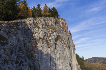 Alpine mountains panoramic view to granite cliff and forest on autumn sunset