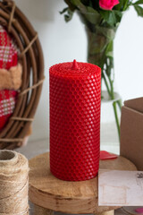 Red wax candle on the table. flowers in the vase. 