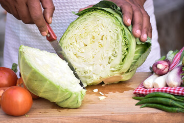 Close up of man's hands while chopping fresh vegetables on cutting board,