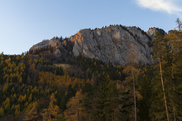 Alpine mountains panoramic view to red granite rock and forest on autumn sunset