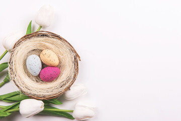 Colorful decorations with Easter egg nest and tulips on white background. copy space, top view