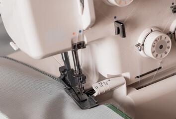 Presser foot of sewing machine threating the textile. Side view.