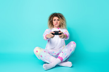 Full lenght photo of sad young curly hairdo lady play station bite lip wear pajama socks isolated on blue background