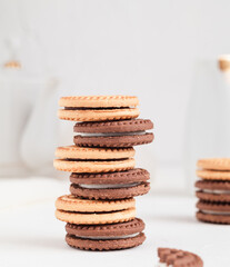 Stack of milk and chocolate cookies with cream close up on a white table. Bakery concept.