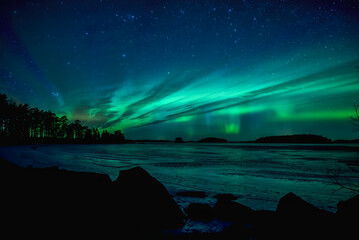 Northern lights dancing over calm lake in Farnebofjarden national park in north of Sweden.
