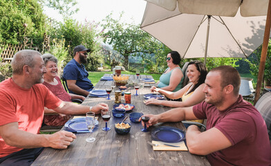 Happy family enjoy barbecue dinner on patio - Multi generational people enjoy summer day outdoor