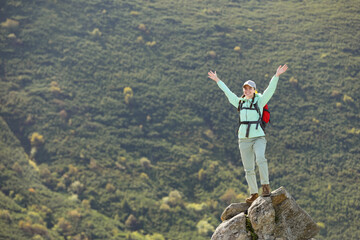 Tourist with backpack standing on peak in mountains