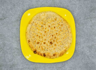 simple Naan in yellow plate top view on grey background